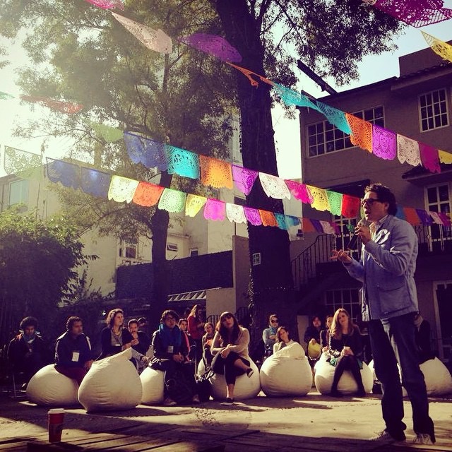 Agustín Mier y Terán dando una conferencia frente a un grupo de jóvenes sentados en el patio
